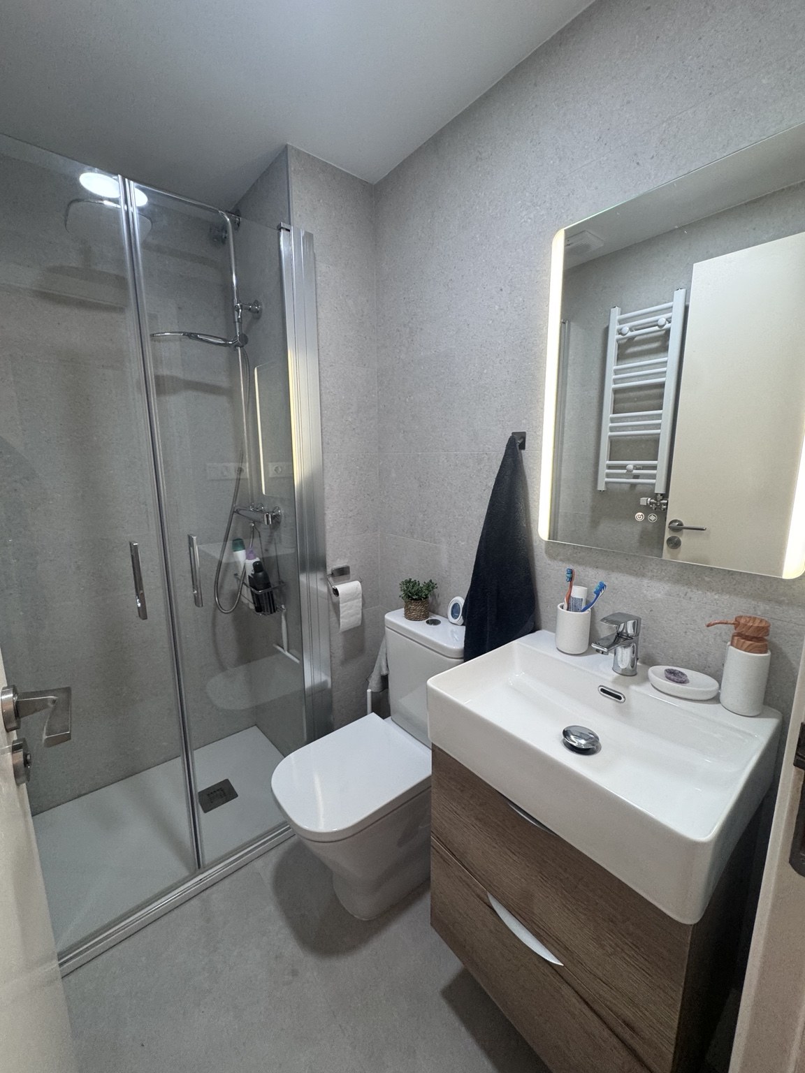 Baño con ducha de mampara de cristal y mueble de lavabo