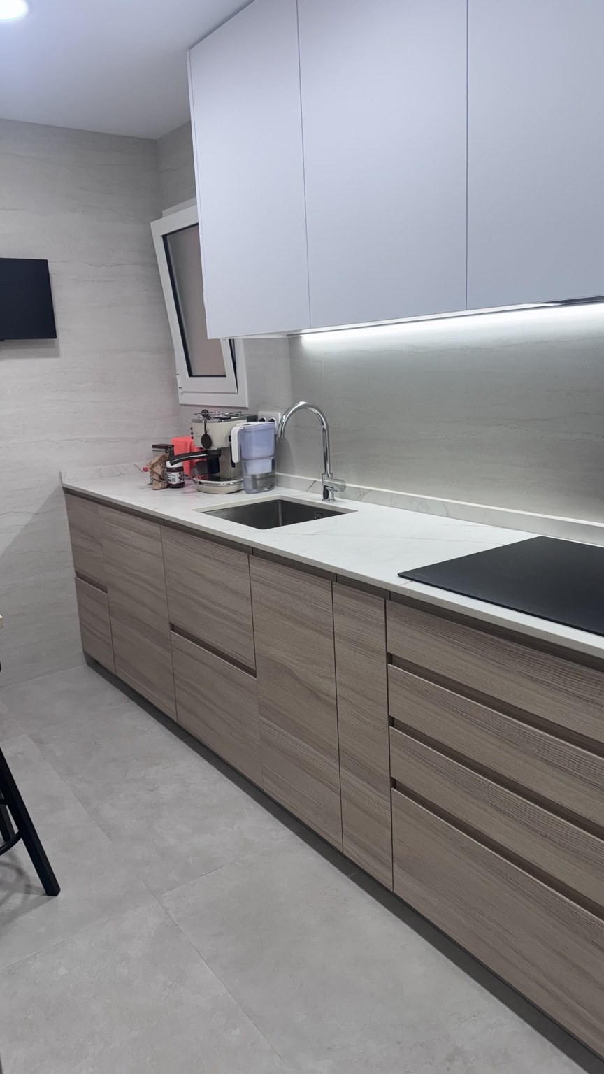 Cocina realizada por IKRA con muebles en acabado madera e iluminación bajo los armarios